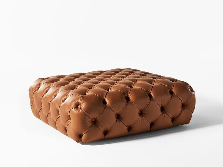 a brown leather ottoman sitting on top of a white floor