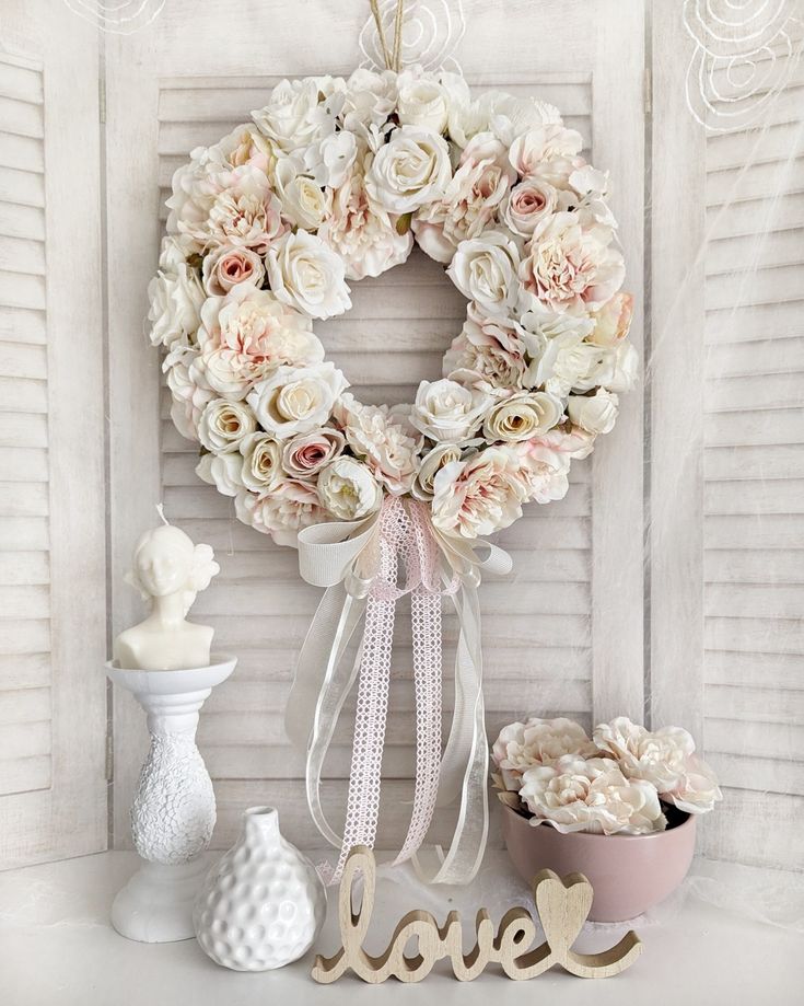 a wreath with the word love hanging on it next to some flowers and vases