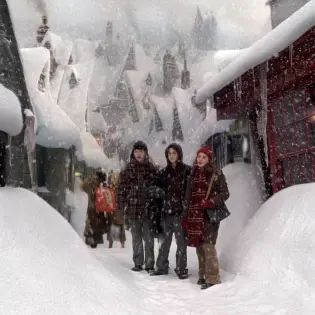 three people are standing in the snow near some houses