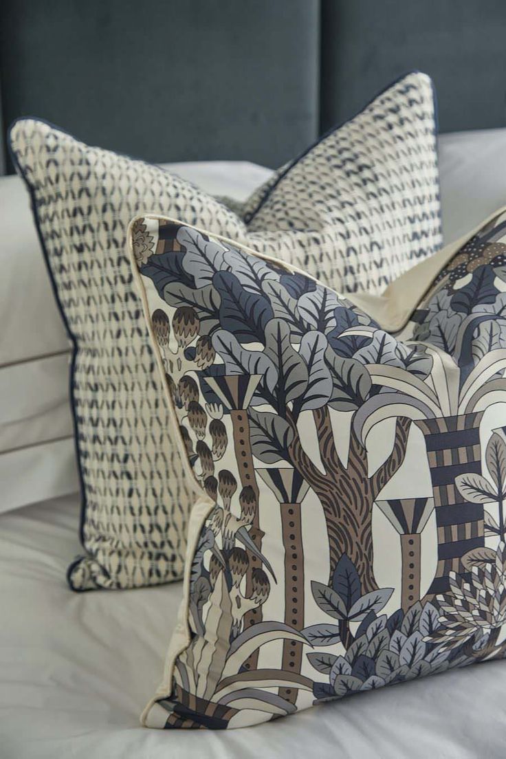 two pillows sitting on top of a bed with white sheets and blue headboard behind them