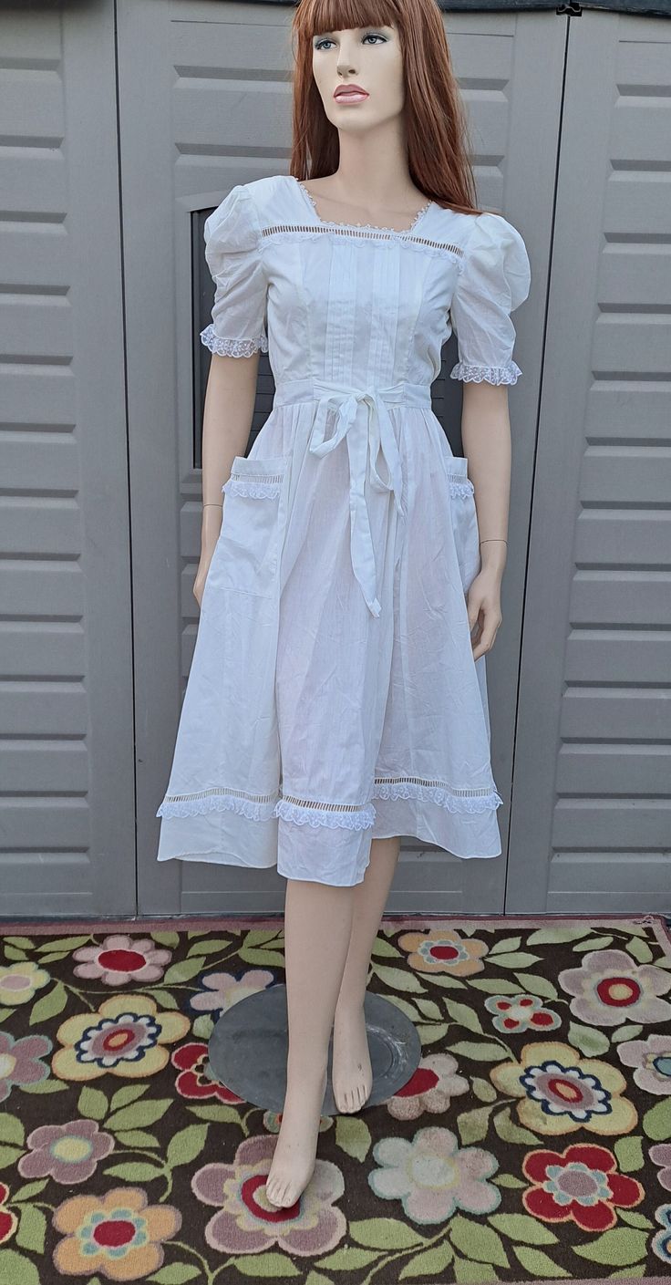 This is a darling 80's Gunne Sax by Jessica dress.  Pretty cream color (it looks white in the pictures but it has more of a light cream tone)  Wraps around in the back and buttons at the waist.  The size tag say size 5 but best to use measurements, may run smaller. It is a  cotton and poly blend and the upper half in lined in a light weight acetate.  has nylon trim.  So darling. It was a little to small on my mannequin so I did have to pin the back waist buttons for the photo.   l Measurements a White Vintage Dress For Garden Party With Short Sleeves, White Vintage Dress With Short Sleeves For Garden Party, White Short Sleeve Vintage Dress For Garden Party, Fitted White Vintage Midi Dress, White Fitted Vintage Midi Dress, Short Sleeve White Vintage Dress, White Knee-length Vintage Dress For Garden Party, White Cotton Lined Vintage Dress, White Retro Knee-length Vintage Dress