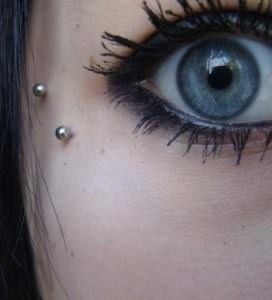 a woman with piercings on her eye looking at the camera