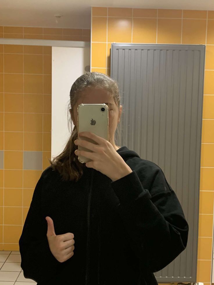 a woman taking a selfie in a bathroom mirror with her phone up to her face