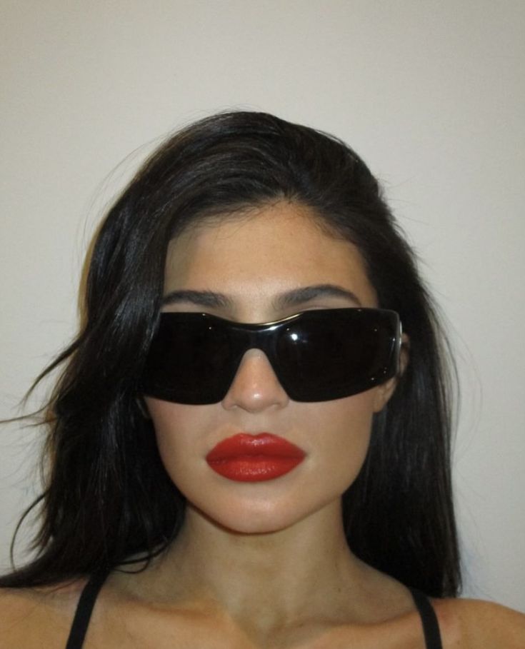 a woman wearing black sunglasses and red lipstick