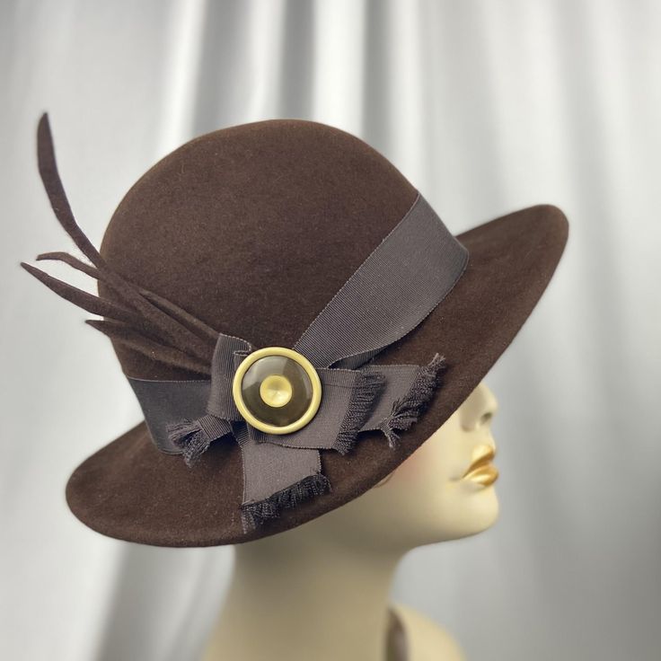 Classic style in brown velour felt! This is the  perfect fall/winter hat. The crown is a bowler style and the 2.25" brim dips on the right side. It was made entirely by hand with a hand-sewn, rolled brim. Trim is vintage quality grosgrain ribbon, felt "feathers" and a vintage button from my collection. Size here is 22" to 22.25. Be sure to measure. Also keep in mind that even though this is a fall/ winter hat, it should be protected from heavy moisture. Thank you for shopping. Vintage Wool Cloche Hat With Flat Brim, Vintage Wool Cloche Hat With Curved Brim, Vintage Brimmed Cloche Hat In Felt, Vintage Fur Felt Cloche Hat For Winter, Vintage Brimmed Felt Cloche Hat, Cloche Hat, Vintage Button, Hats Vintage, Grosgrain Ribbon