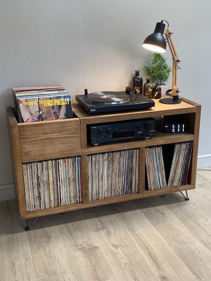 a record player sitting on top of a wooden shelf next to a lamp and records