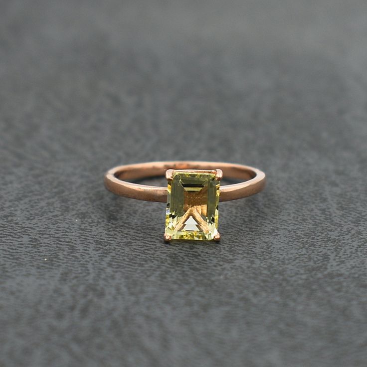 a yellow diamond ring sitting on top of a gray surface with an orange stone in the center