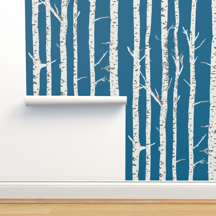 the wall paper has been painted with white birch trees on blue and is next to a roll of toilet paper