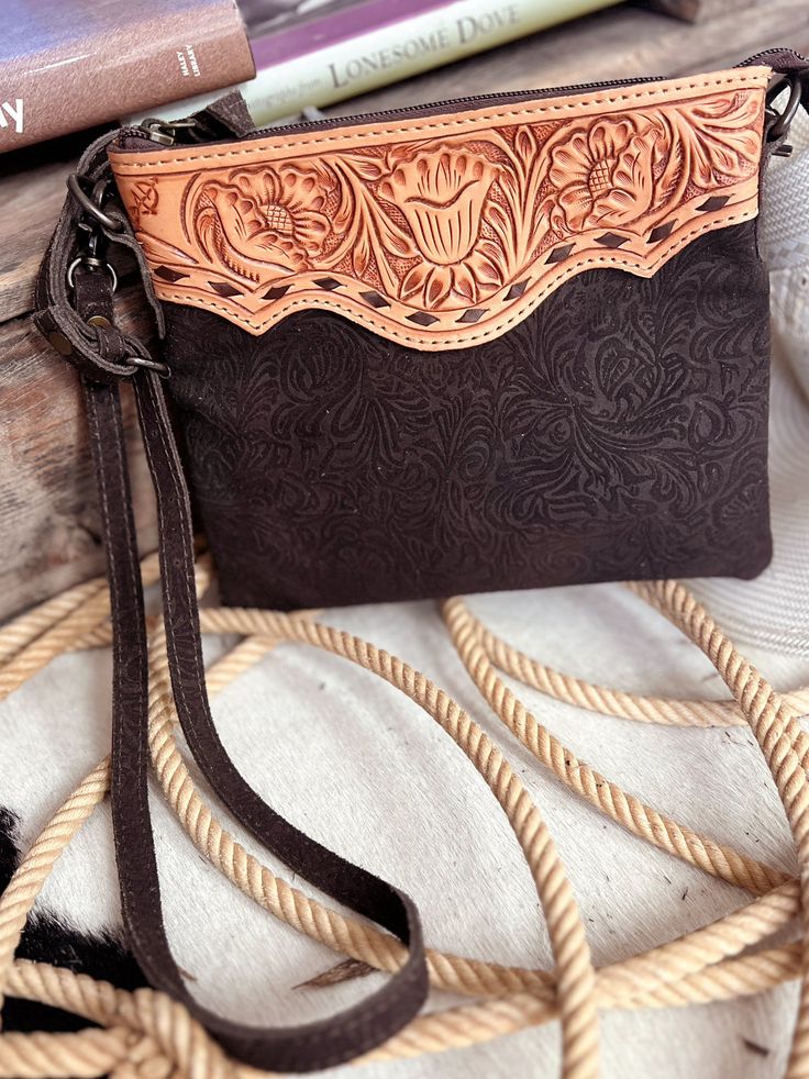 Darling Tooled Not Fooled Leather Crossbody Bag | Gussied Up Online Indulge in the timeless elegance of the Darling Tooled Not Fooled Leather Crossbody. Crafted from high quality, genuine leather, this western-style bag boasts a beautiful tan tooled trim and a rich chocolate brown embossed suede body. With a removable and adjustable strap, and a convenient zip-top closure, this pouch-style bag is both stylish and functional. One compartment with an inside zipper pocket, outside zipper pocket and Hand Tooled Brown Bags For Rodeo, Brown Hand Tooled Bag For Rodeo, Hand Tooled Brown Bag For Rodeo, Brown Rectangular Bag For Rodeo, Rectangular Brown Bag For Rodeo, Hand-tooled Saddle Bags, Hand Tooled Western Bags, Western Style Hand Tooled Brown Bag, Western-themed Brown Leather Shoulder Bag