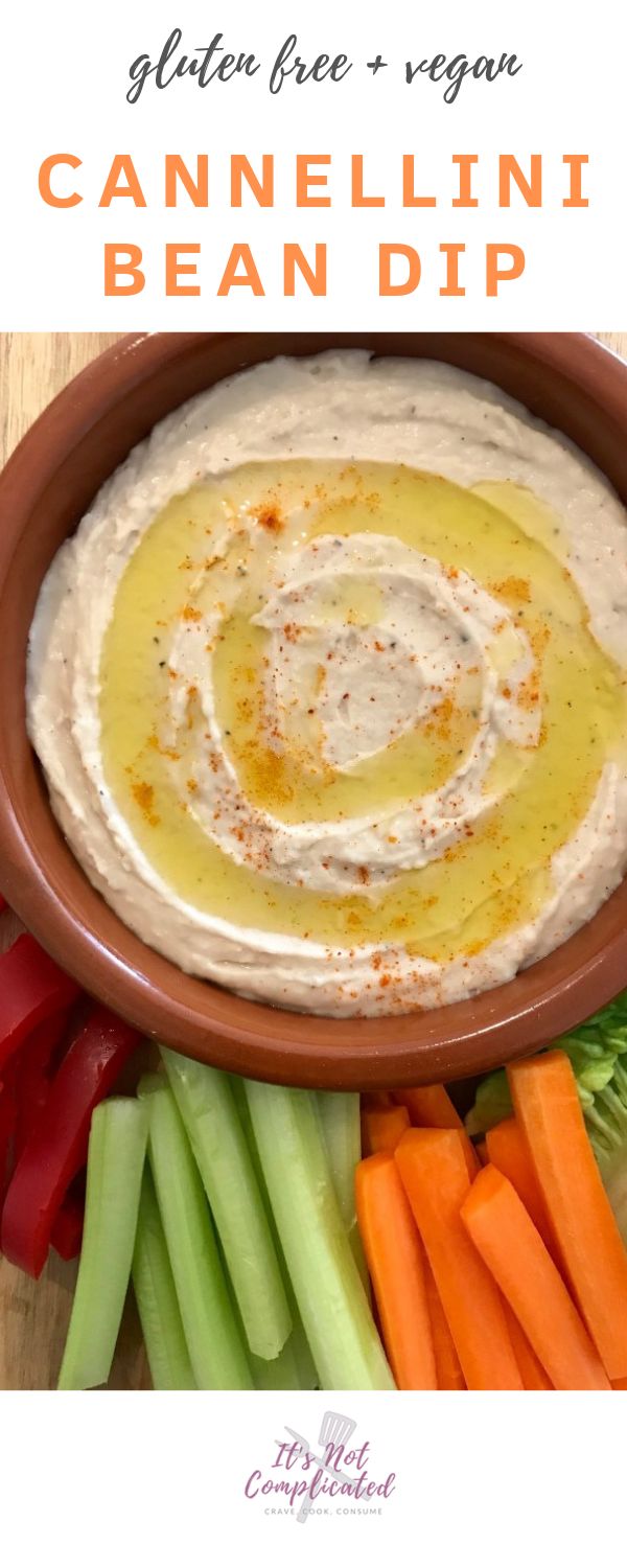 a bowl filled with dip surrounded by carrots and celery