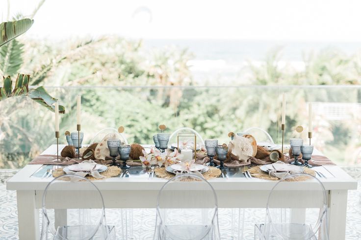 the table is set with clear chairs and plates