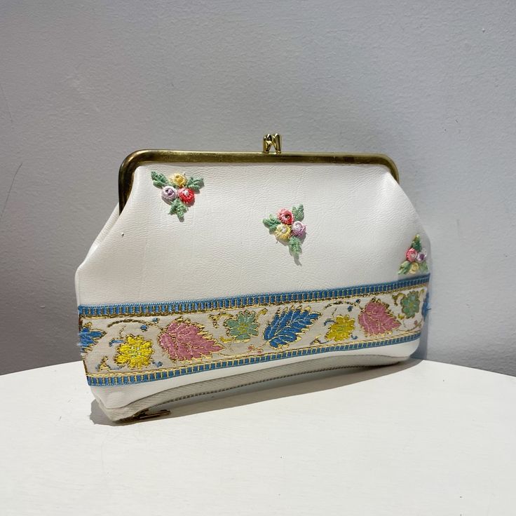 Vintage 60s White Vinyl Floral Embroidered Kiss Lock Clutch/Purse, Cosmetics Bag. This Purse Was Never Used. White Vinyl With Embroidered Floral,Pink, Blue, Yellow, Green And Red, On Front. Floral Embroidered Ribbon With Gold Accents Along Bottom Front. Deep Zippered Compartment On Bottom. Green, And Tan Floral Lined. Interior Is Lined With Green Vinyl. Gold Tone Frame And Kiss Lock. Tag From Sale Left A Tiny Hole On Side Front, Gold Tone Frame Has Some Fading (See Pics) Otherwise, No Flaws, Cle White Rectangular Coin Purse, Retro Pouch Clutch For Daily Use, White Retro Pouch Bags, White Rectangular Coin Purse For Daily Use, Embroidered White Rectangular Pouch, White Embroidered Rectangular Pouch, Embroidered Cream Rectangular Clutch, Cream Embroidered Rectangular Clutch, Compact White Bag For Daily Use