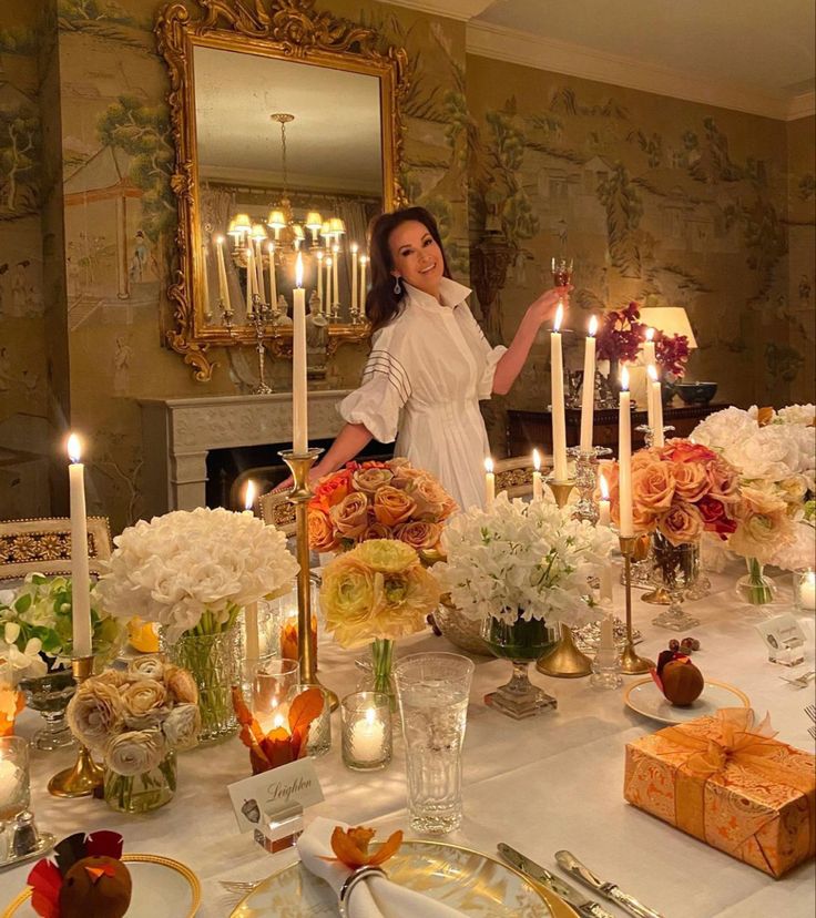 a woman standing in front of a table filled with flowers and candles