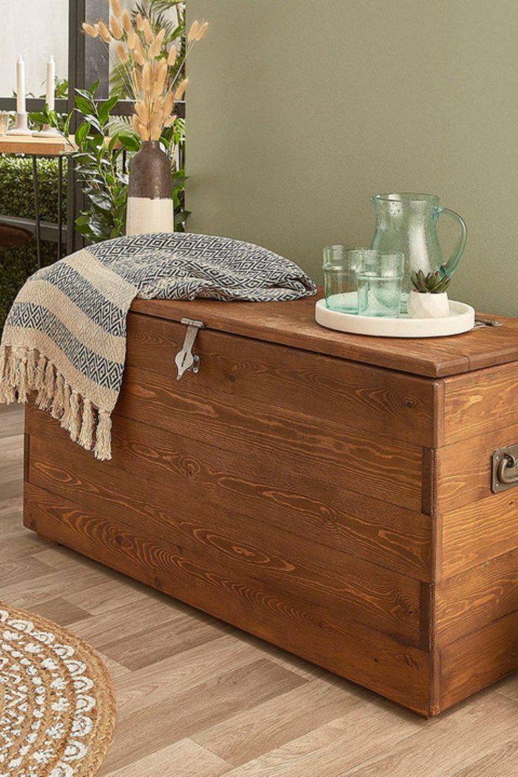 a wooden trunk sitting on top of a hard wood floor next to a potted plant