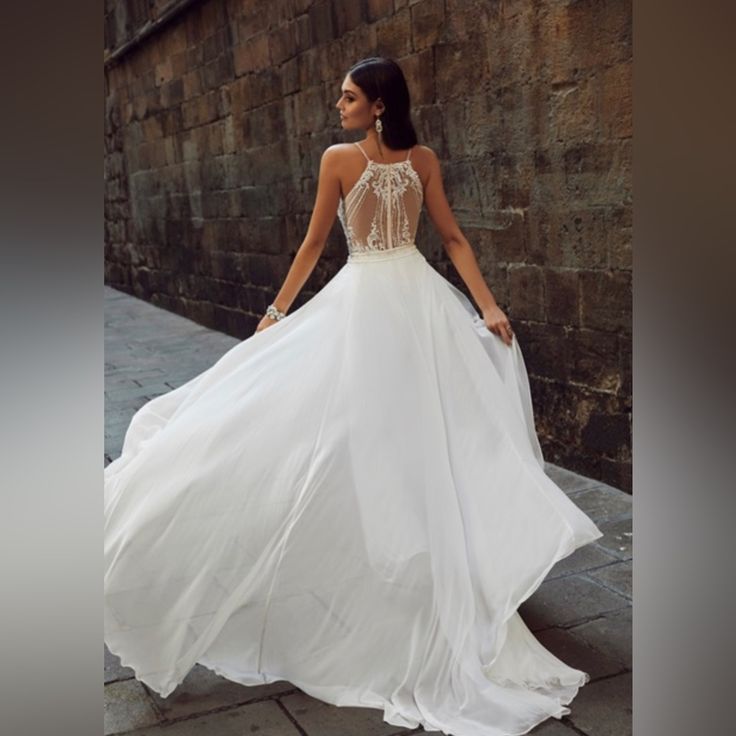 a woman in a white dress is standing on the sidewalk with her back to the camera