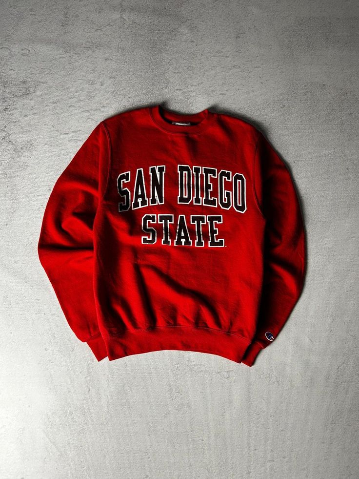 Vintage Champion San Diego State Crewneck Sweatshirt, Vintage Sweatshirt, Champion Sweatshirt Men's XS Size On Label: XS Recommended Size: Men's XS Measurements: Pit-to-Pit: 18" Length: 26" Collegiate Winter T-shirt For Streetwear, College Crew Sweater With Logo Print, Red Crew Sweatshirt With Letter Print, University Logo Long Sleeve Tops For Streetwear, Collegiate Crew Neck T-shirt For Winter, Winter Collegiate Crew Neck T-shirt, Red Collegiate Cotton Sweater, Winter College T-shirt With Logo Print, Collegiate Hoodie With Logo Print And Crew Neck