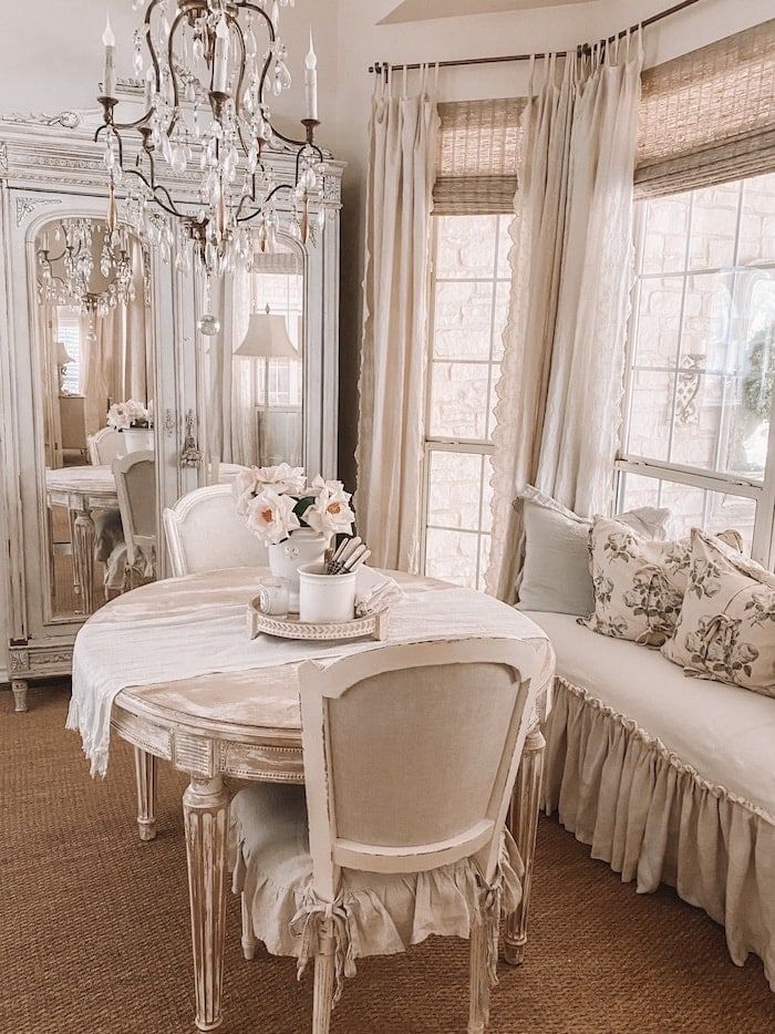 a white dining room table and chairs with chandelier in the corner behind it