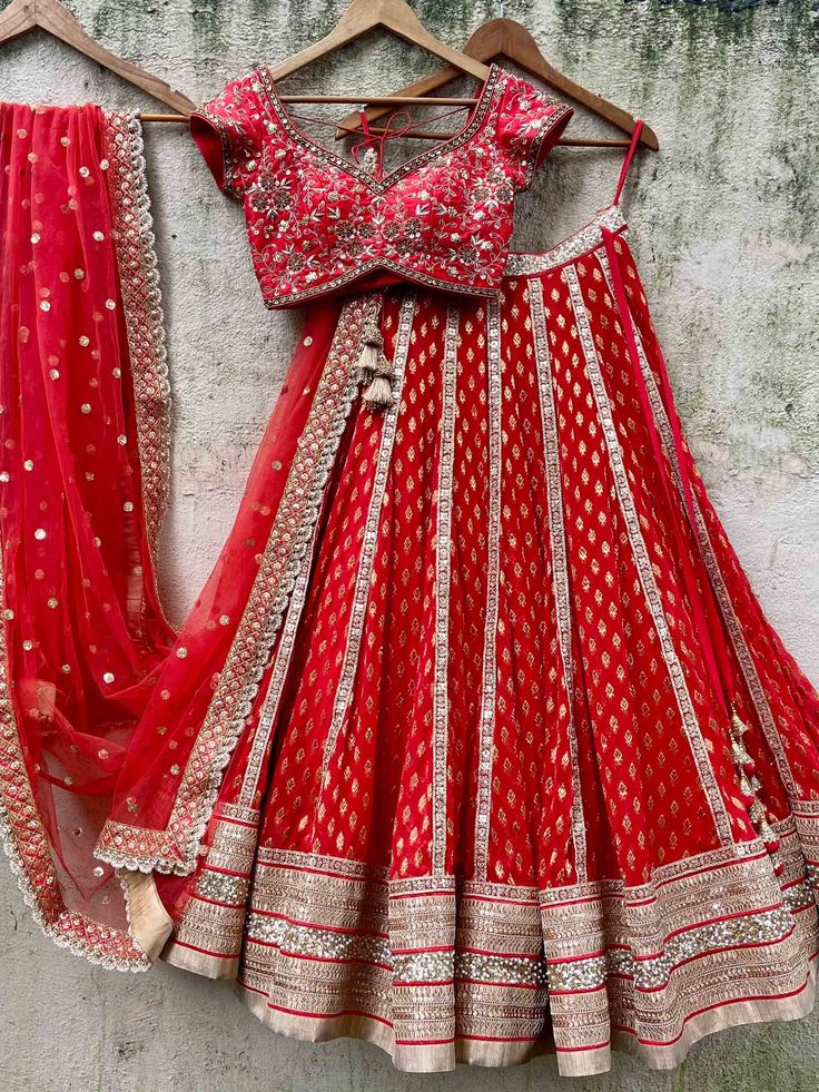 A three-piece red bridal sharmily embroidered lehenga set from the Priti Sahni collection. This beautiful and graceful georgette red butti bridal panel lehenga with a heavy border of gota, pearl, sequin, zari detail is paired with a red raw silk blouse with zardozi, sequin, & hand-embroidery work. The zari panelled lehenga has side hanging ball tassels to the waistline. And the blouse has a sequin-bead tassel tie-up at the back. This outfit is completed with a red tulle sequin butti dupatta with Anarkali Georgette Lehenga For Traditional Ceremonies, Red Fitted Lehenga For Traditional Ceremonies, Red Semi-stitched Sets With Intricate Embroidery, Red Dola Silk Lehenga With Dupatta, Red Semi-stitched Anarkali Lehenga, Red Anarkali Lehenga With Intricate Embroidery, Red Dola Silk Lehenga For Traditional Ceremonies, Red Georgette Sets With Dupatta, Red Dola Silk Choli For Traditional Ceremonies