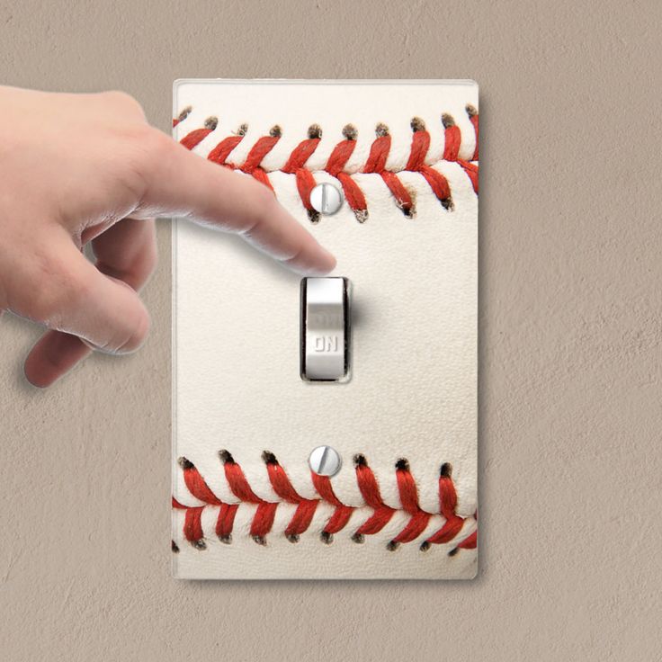 a baseball themed light switch plate with a hand pointing at it