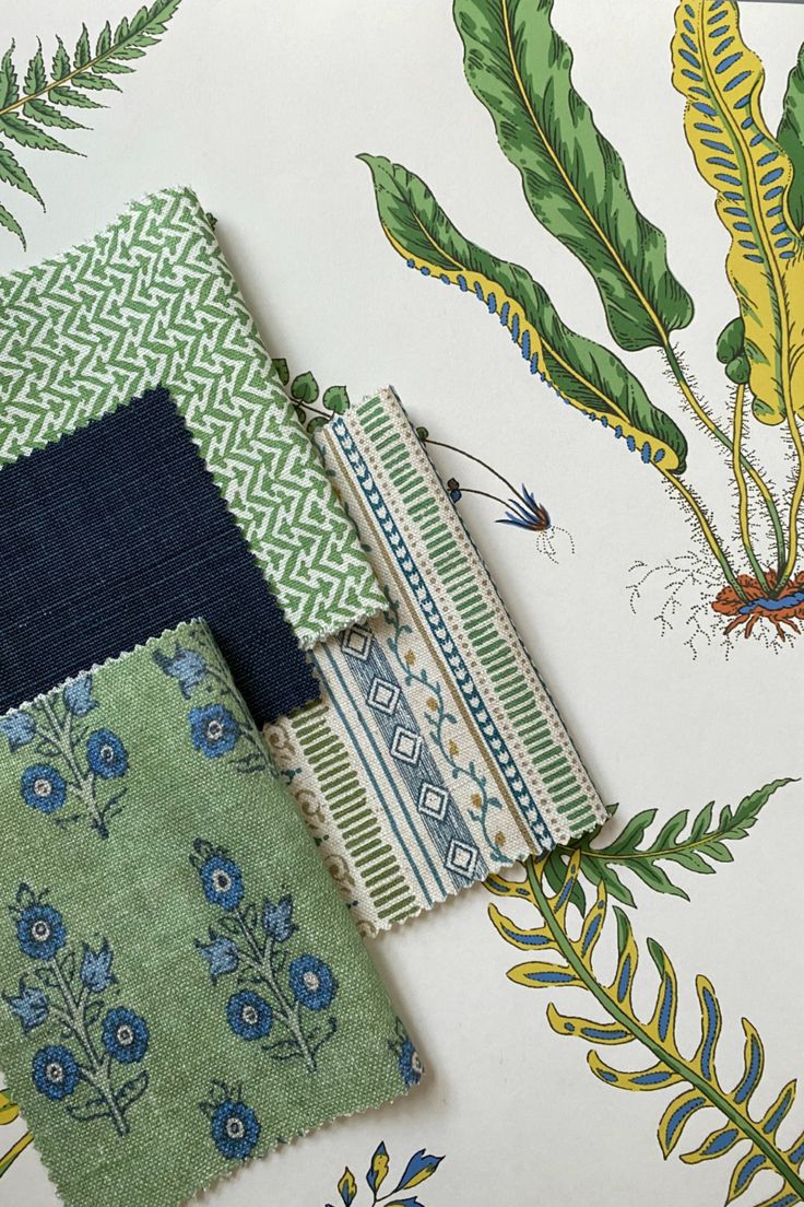 several different fabric samples are laid out on a tablecloth with blue and green designs