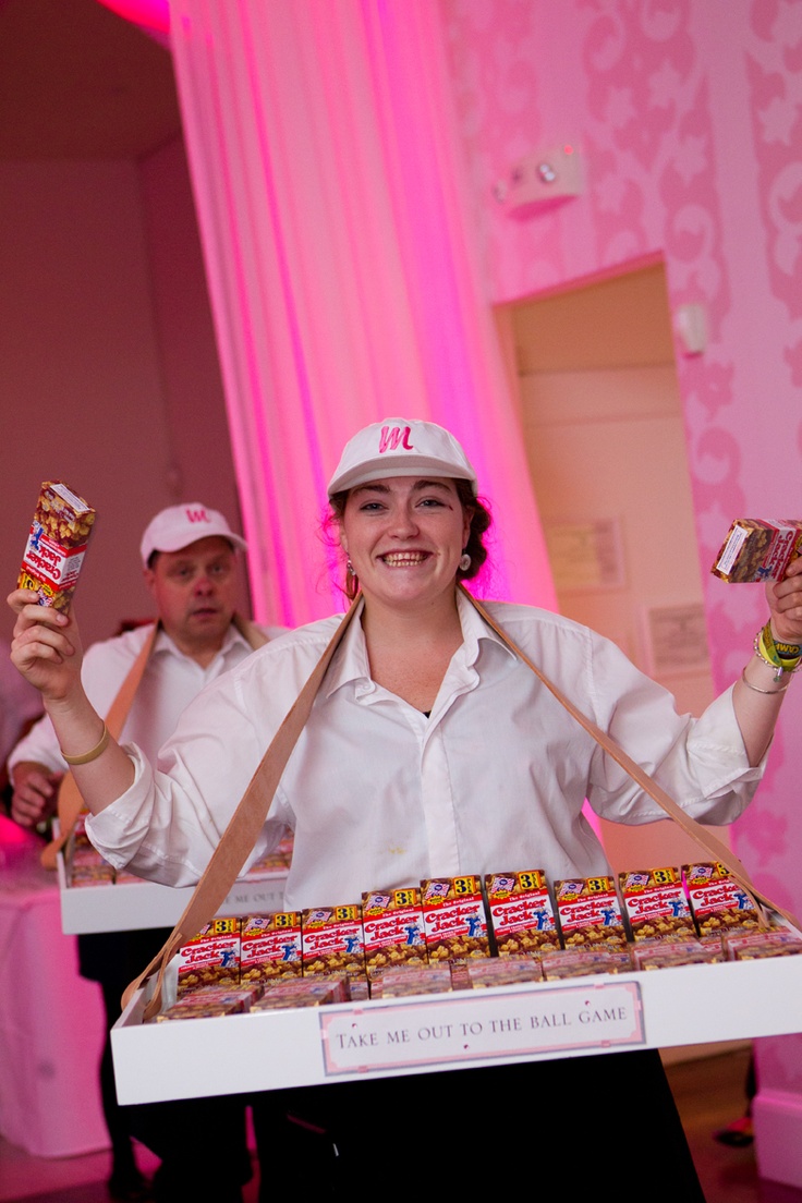 a woman holding up a box of candy while standing next to a man in a pink room