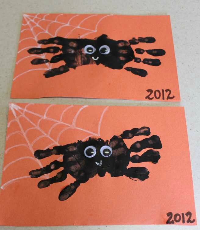 two handprinted pictures of spider on orange paper with numbers 2012 and 2012 written in black