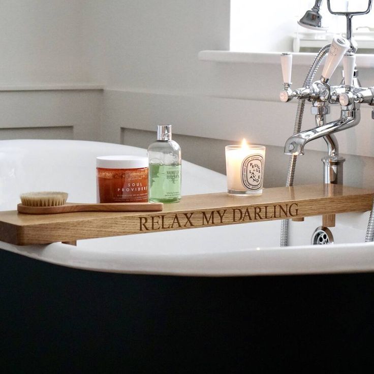 a bathtub with candles and soaps on it in front of a window that reads relax my daring