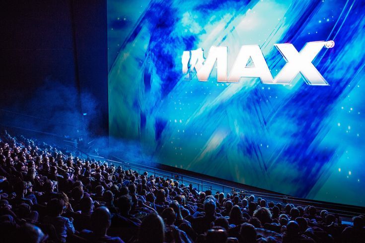 a large screen with the word max projected on it in front of an auditorium full of people