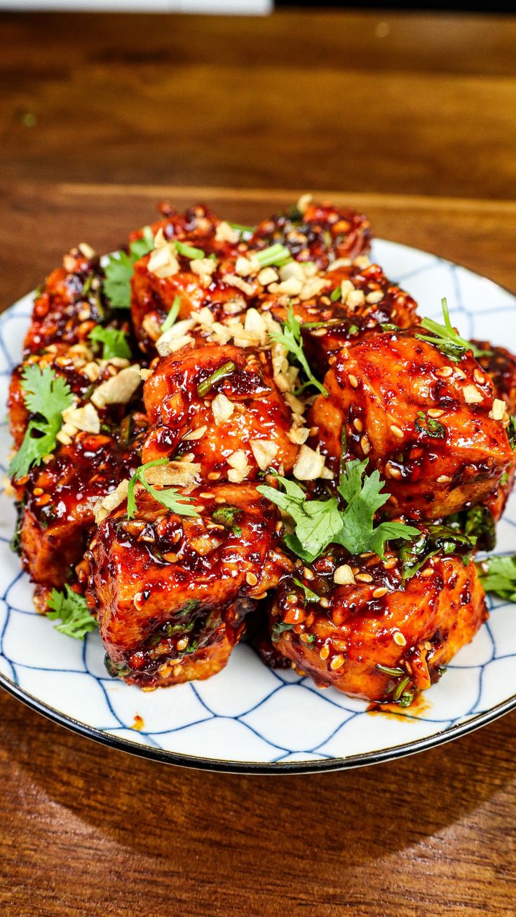 a white plate topped with meat covered in sauce and garnished with cilantro