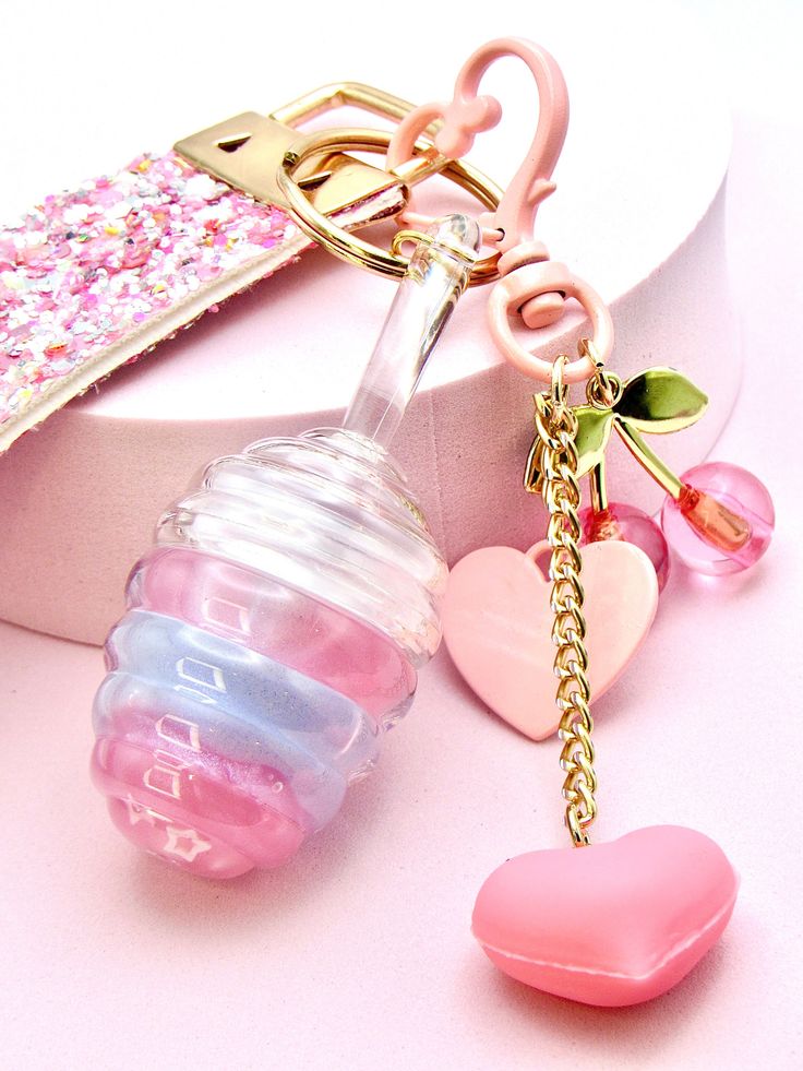 a pink pacifier keychain with two hearts attached to it