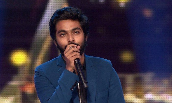 a man in a blue suit holding a microphone to his mouth while standing on stage