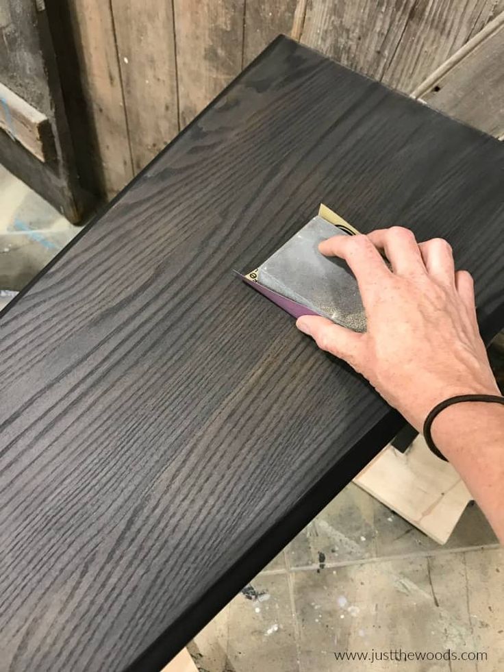 a person's hand on top of a wooden table with a book next to it