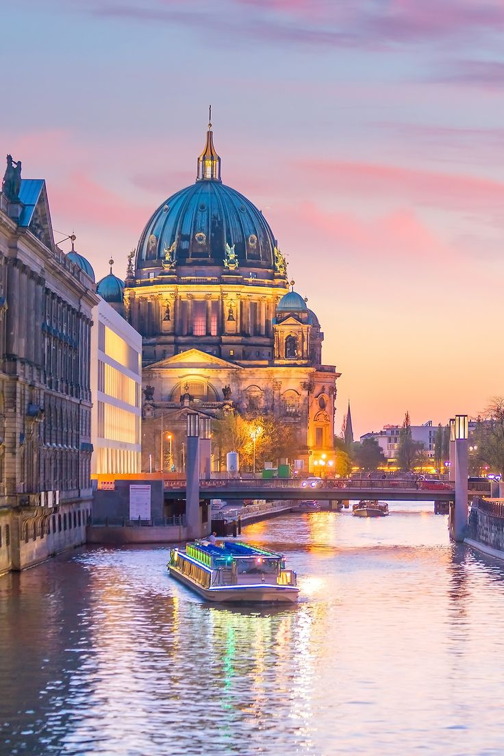 a boat is going down the river in front of a building with a dome on top