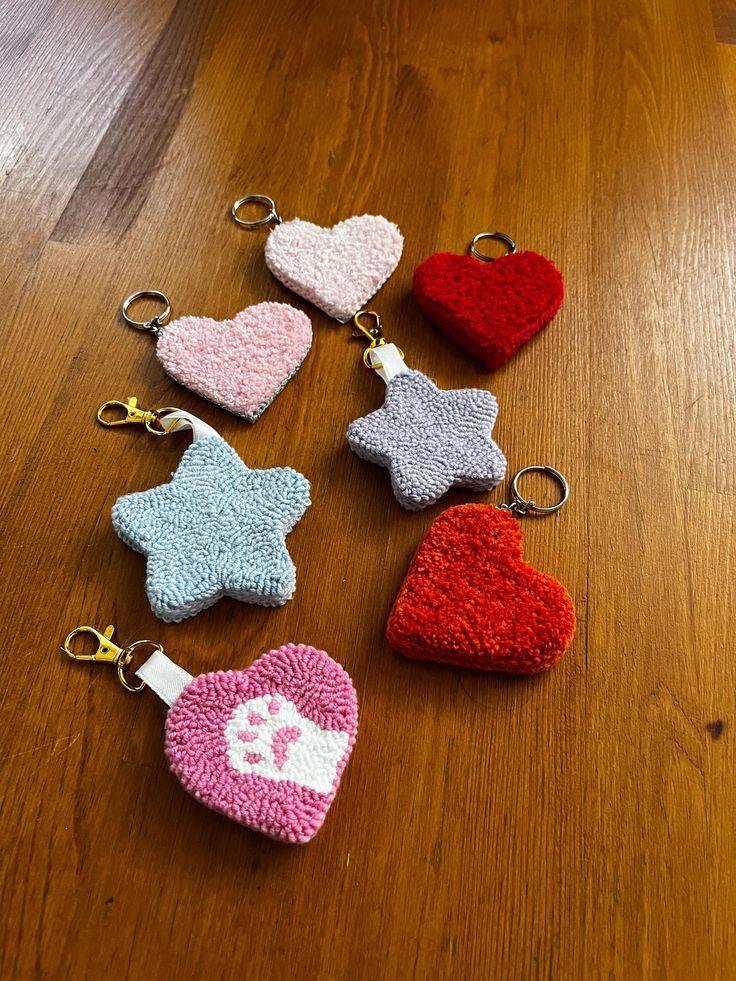 six crocheted heart shaped keychains on a wooden table with one red, one blue and one pink