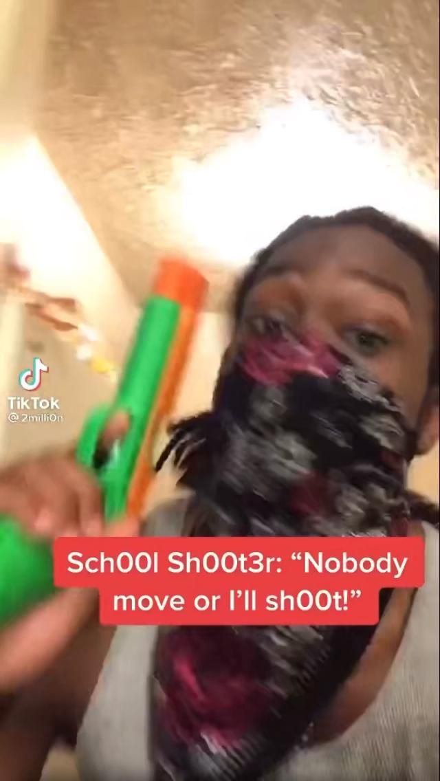 a woman holding a green and orange blow dryer in her hand with the words school shots nobody move or i'll shoot