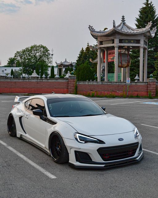 a white sports car parked in a parking lot next to a chinese style pagoda building