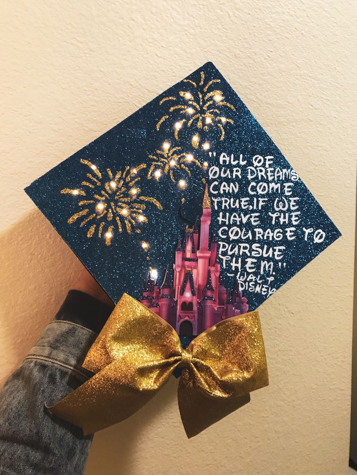 someone is holding up a graduation cap with fireworks in the sky above it and writing on it