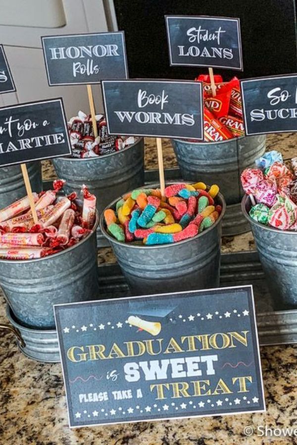 buckets filled with candy and graduation signs on top of a granite counter next to a sign that says congratulations sweet treat