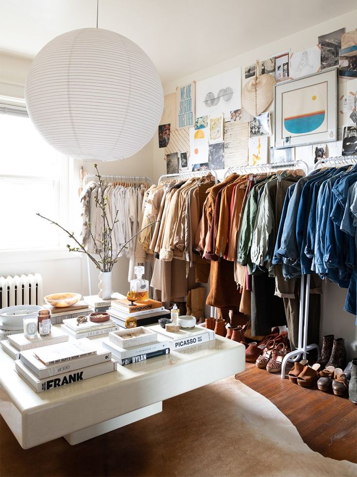 a room filled with lots of clothes and shoes on top of a white table next to a window