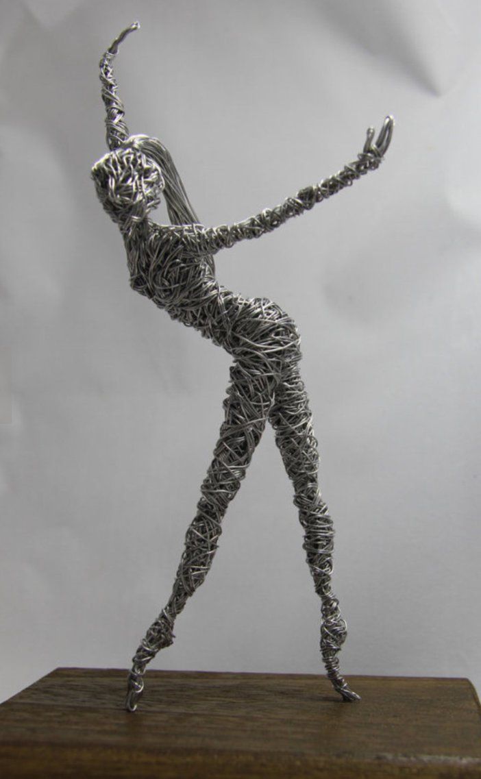 a wire sculpture of a woman holding a tennis racquet on top of a wooden table