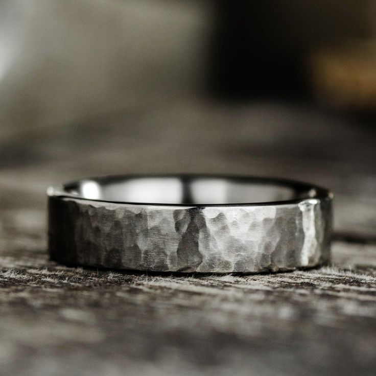 a silver ring sitting on top of a wooden table next to a piece of wood