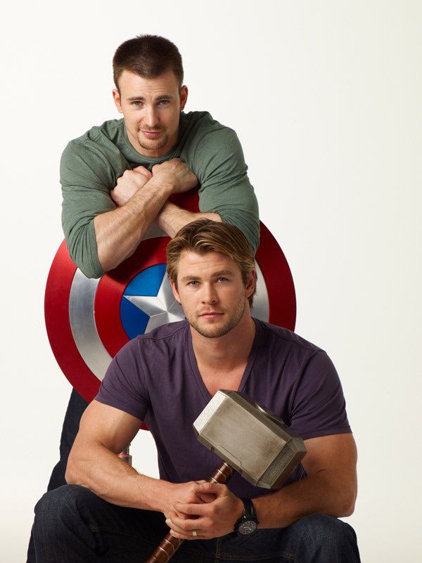 two men sitting on top of each other in front of a captain america shield and hammer