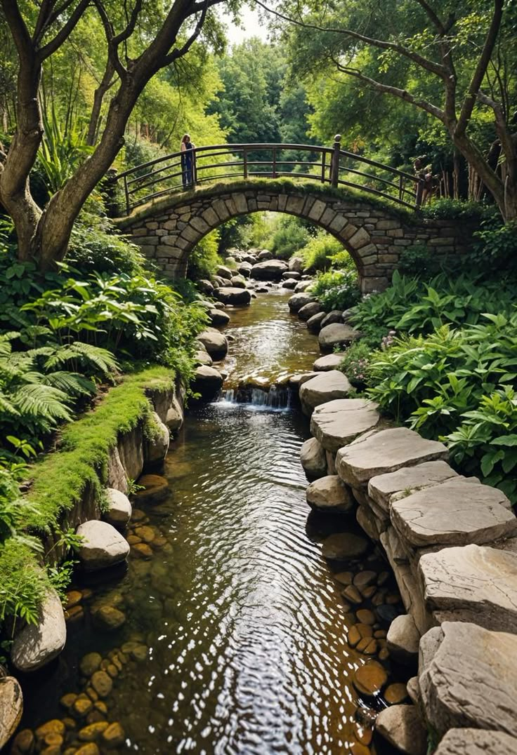 a man standing on a bridge over a small stream in the middle of a forest