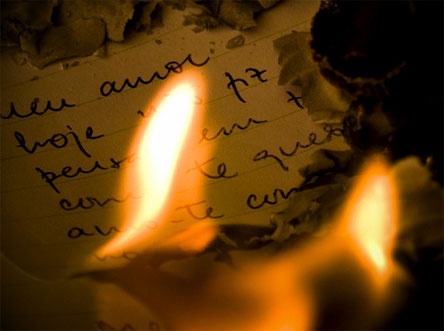 two lit candles sitting next to each other on top of a piece of paper with writing on it