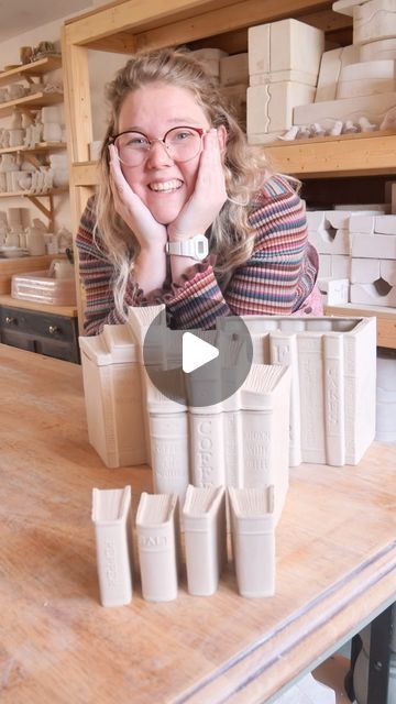 a woman sitting at a table surrounded by cups