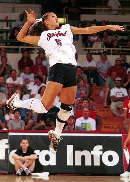 a woman jumping in the air to hit a volleyball