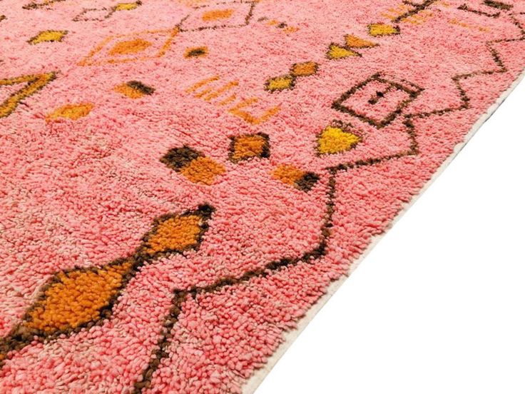 a pink rug with an orange and yellow design on the bottom is shown in full view