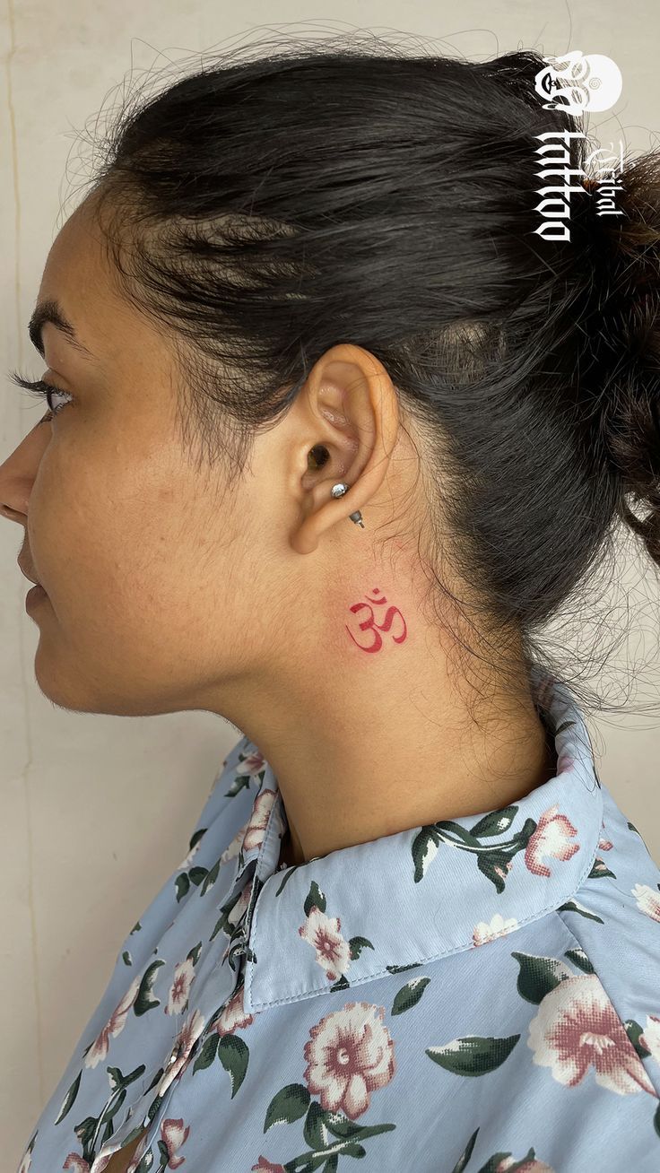 a woman with a small tattoo on her neck and behind her ear is an om symbol