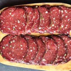 several slices of raw ground beef on a cutting board