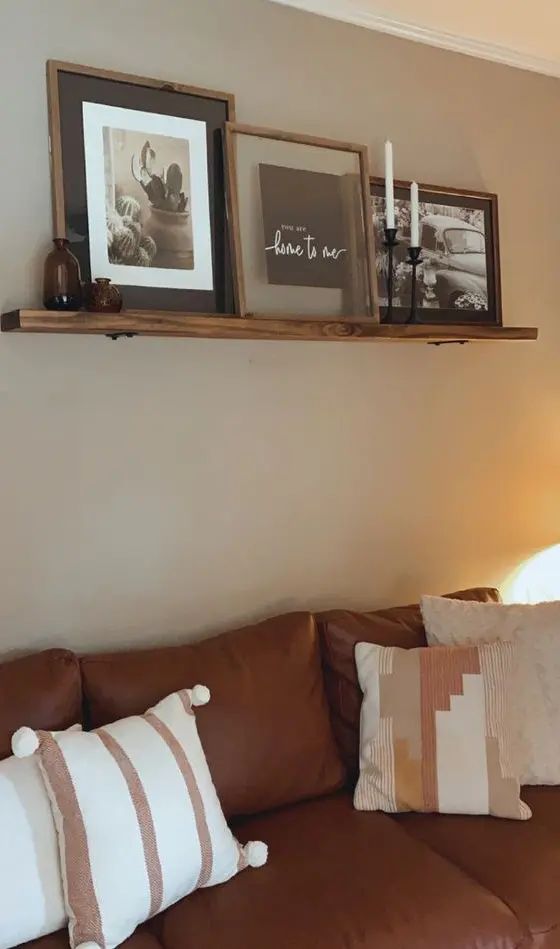 a living room filled with brown couches and pictures on top of the wall above them